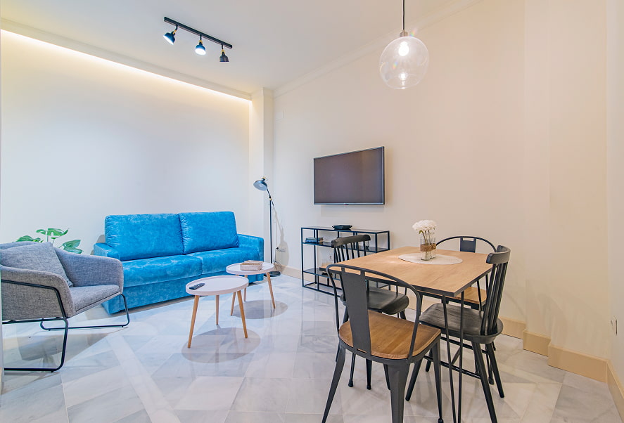 Zona de estar, con sofá azul, muebles de diseño y TV de pantalla plana