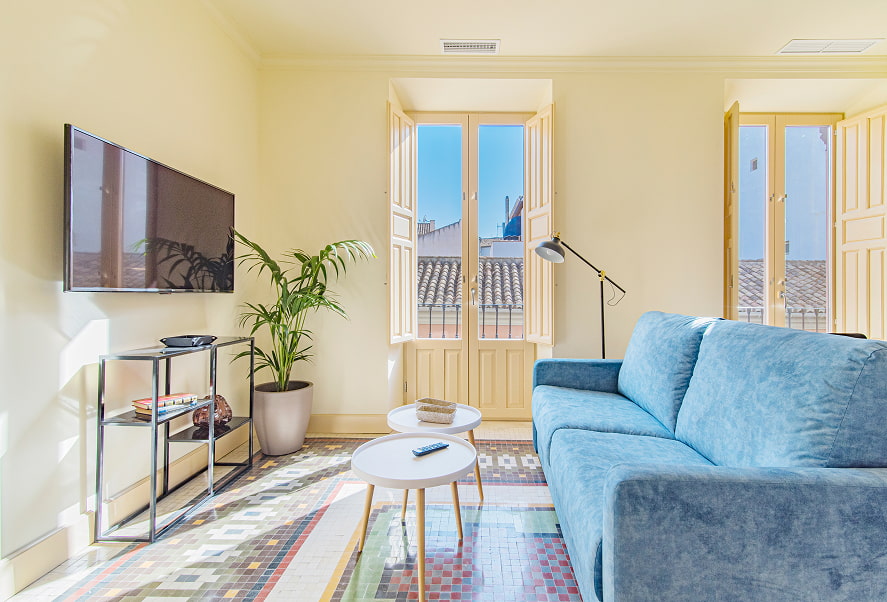 Zona de estar, con sofá azul, muebles de diseño y TV de pantalla plana