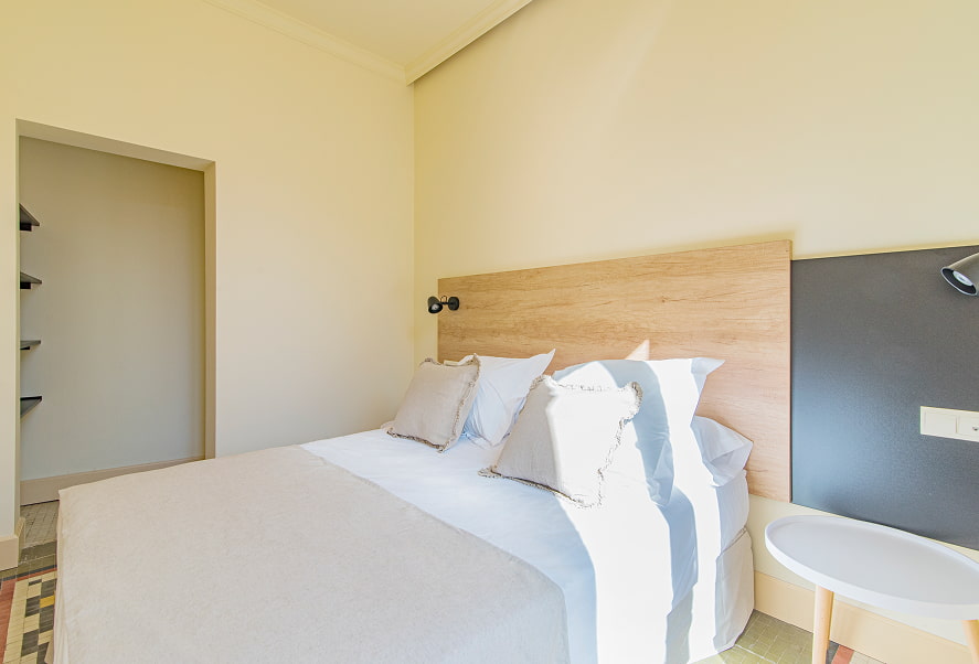 Vista lateral de la habitación con cama doble y cabecero de madera