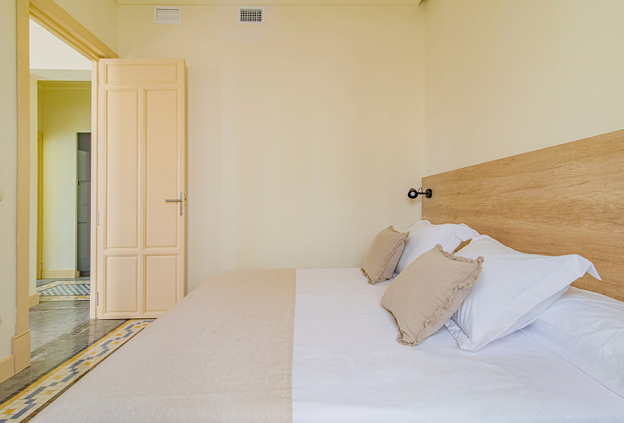 Vista lateral de la habitación con cama King Size y cabecero de madera